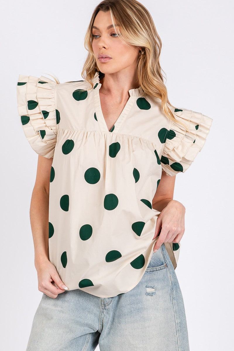 Woman wearing a beige blouse with black polka dots