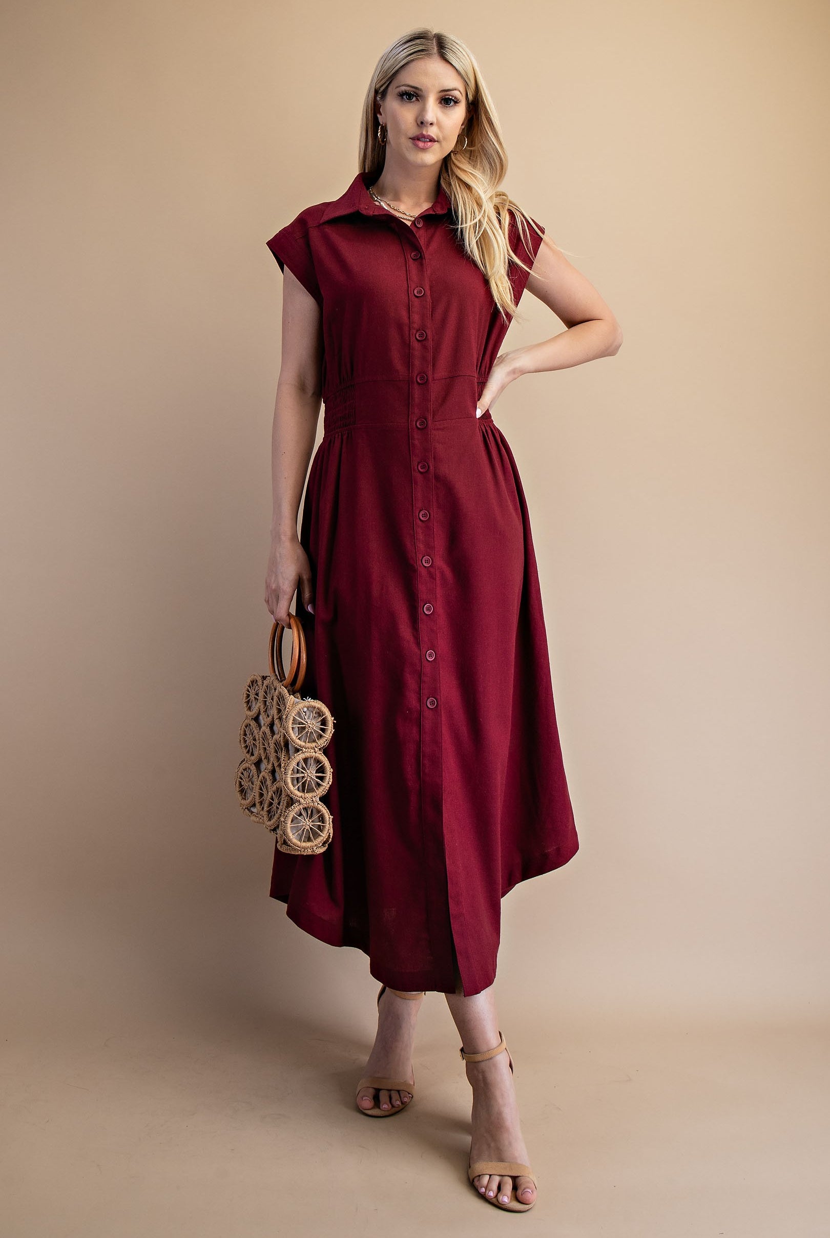 Model wearing burgundy linen dress with tan shoes and a purse in her hand