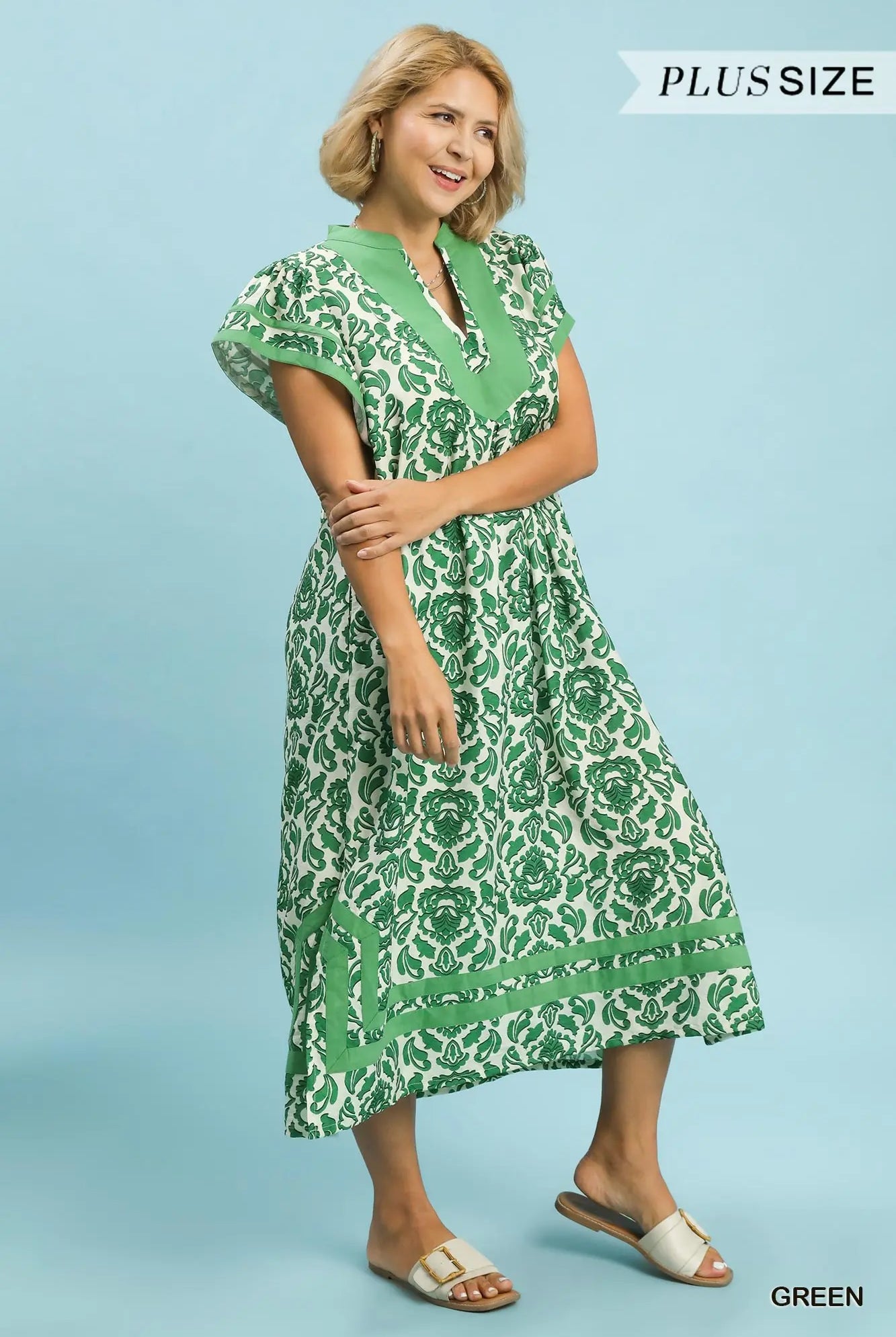 Woman wearing a green patterned dress on a blue background