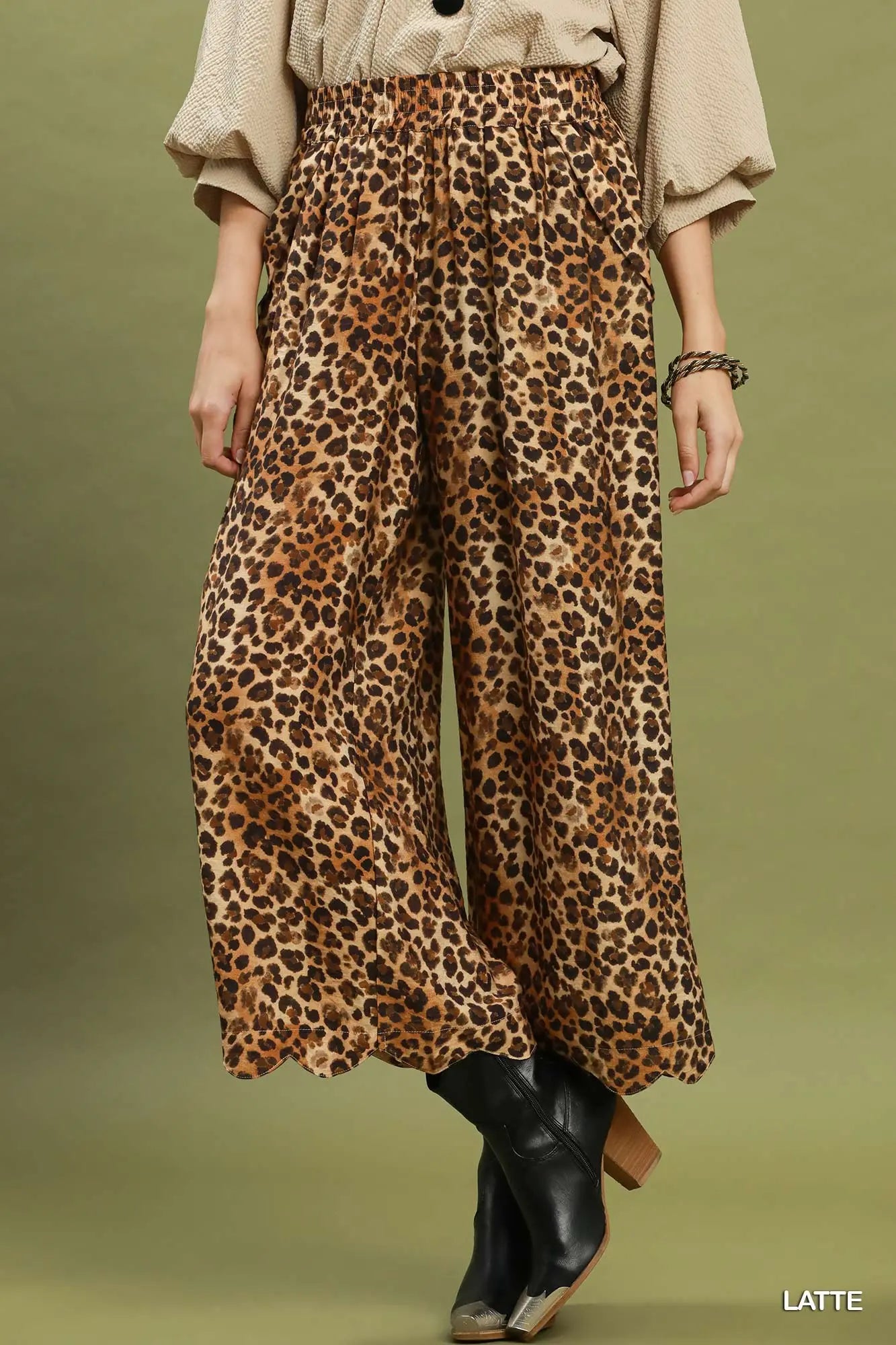 Model wearing leopard black boots against a green background
