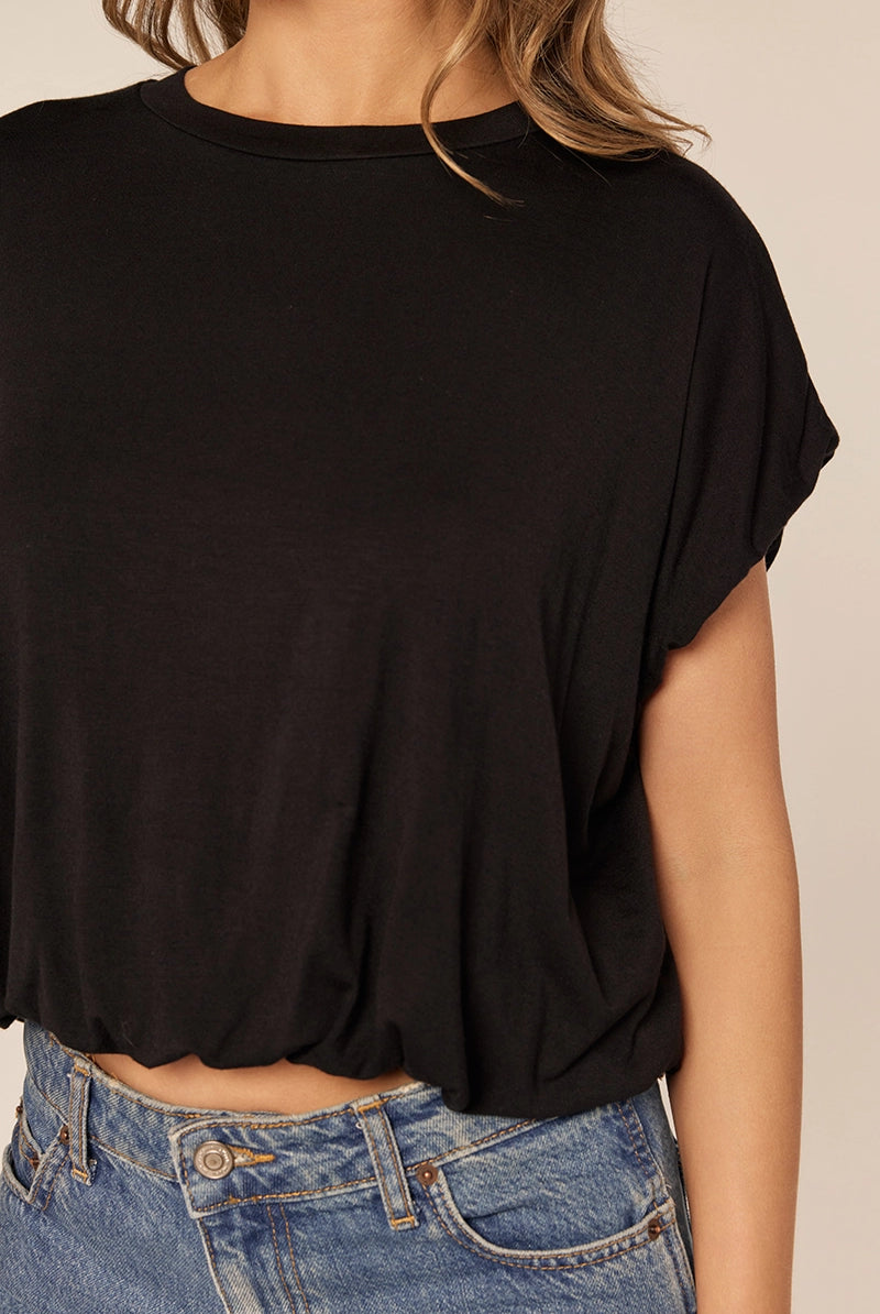Black top worn by a person with a beige background