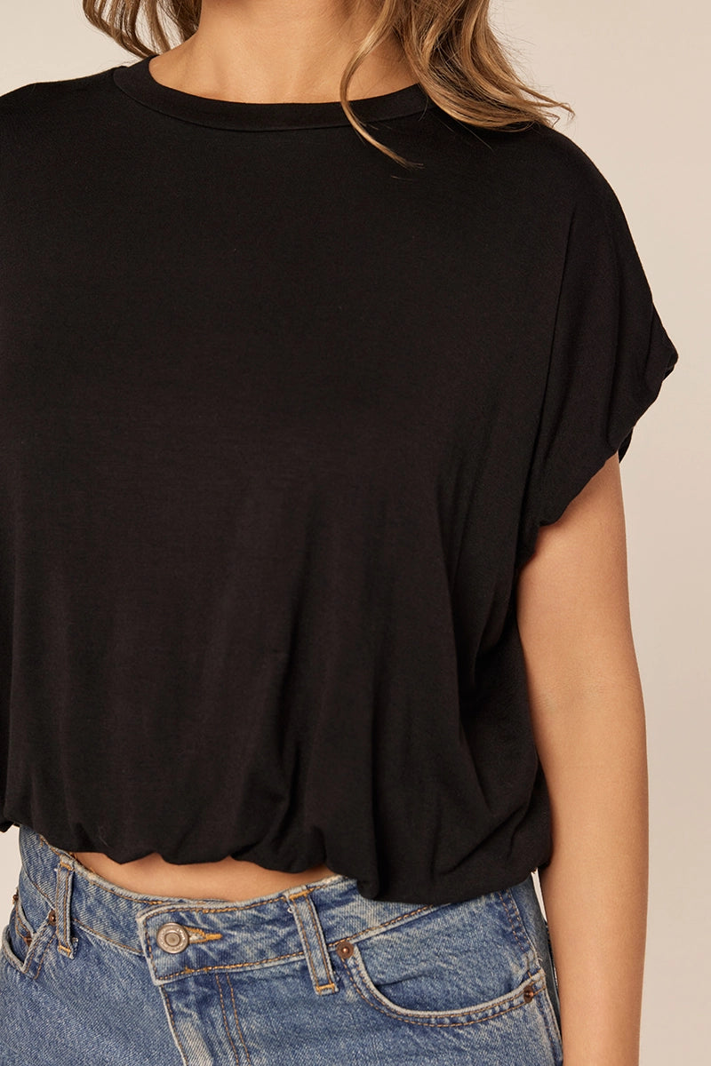 Black top worn by a person with a beige background