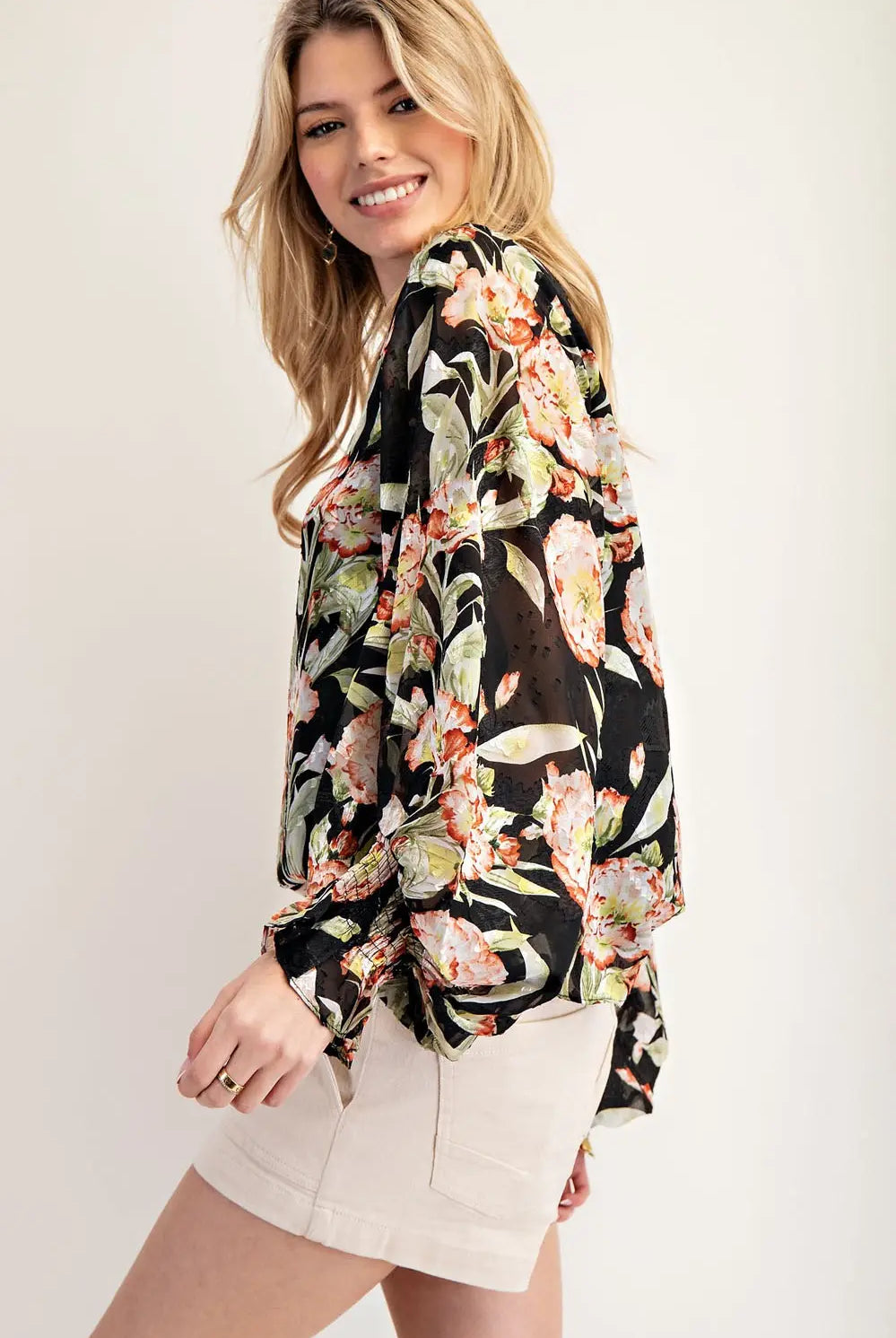 Side view of model wearing black floral top and cream shorts