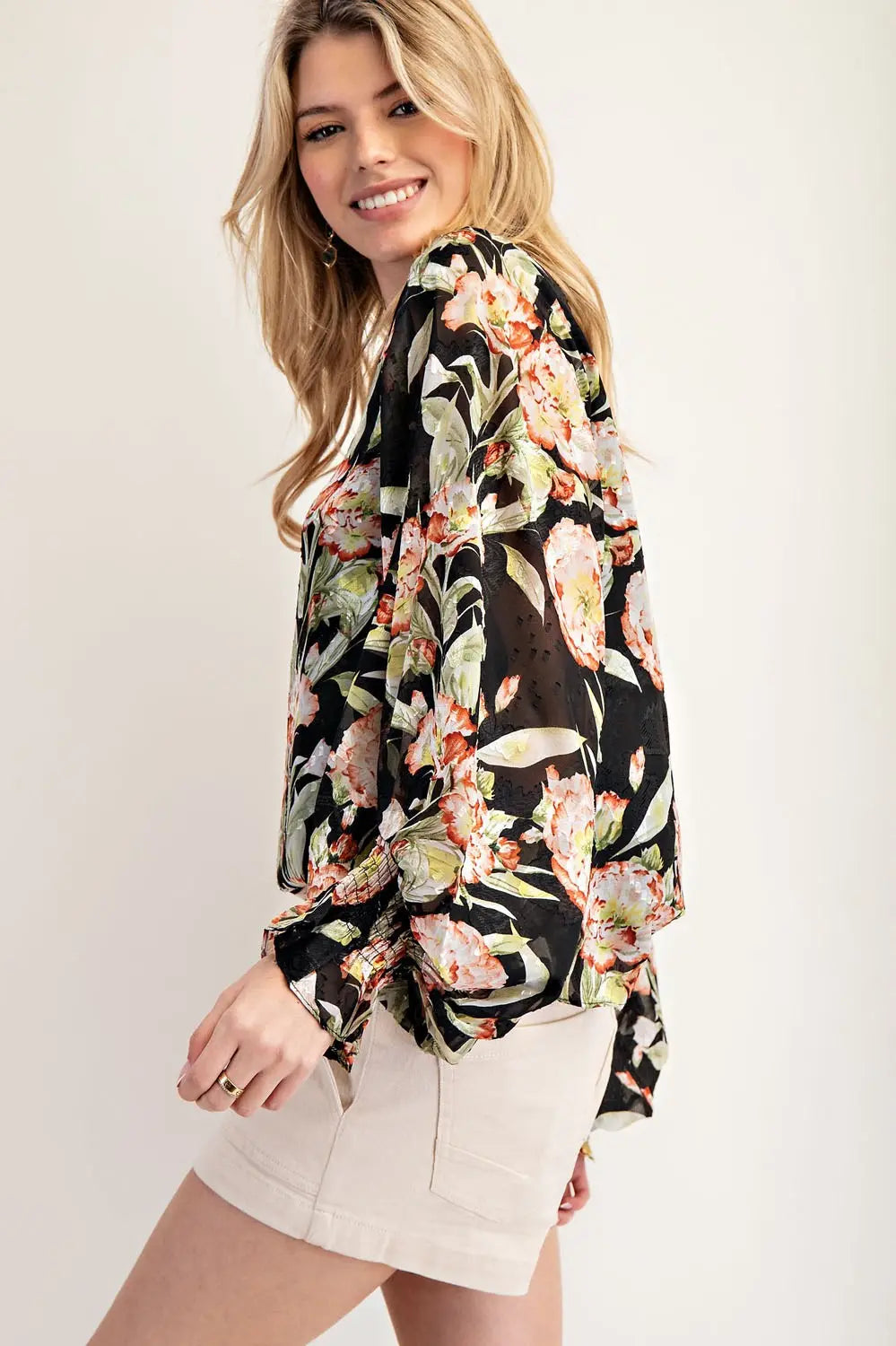 Side view of model wearing black floral top and cream shorts