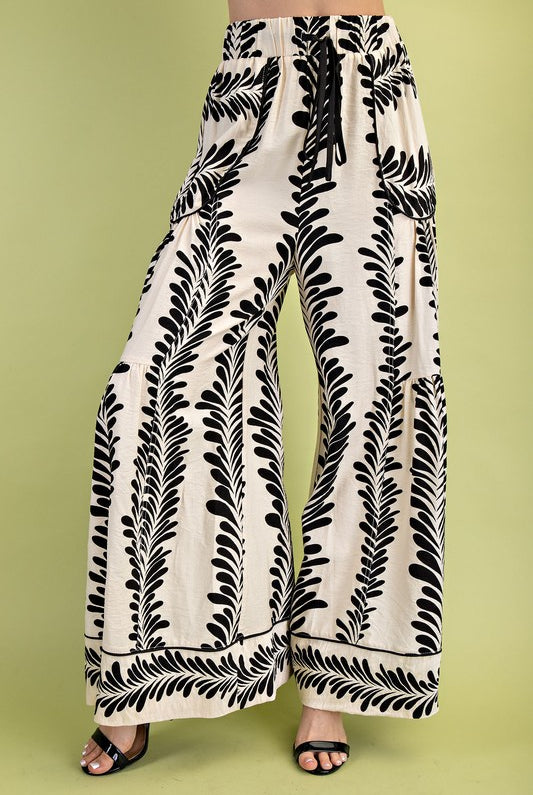 Wide-leg pants with black leaf pattern on a green background