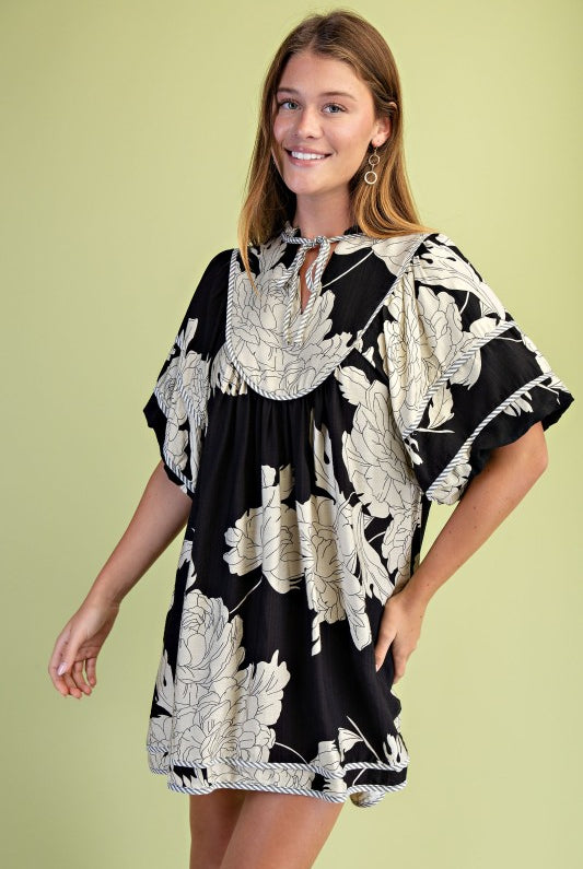 Woman wearing a black and white floral dress against a light green background