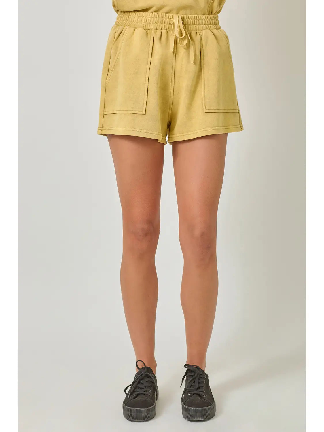 Person wearing mustard yellow shorts on a plain background