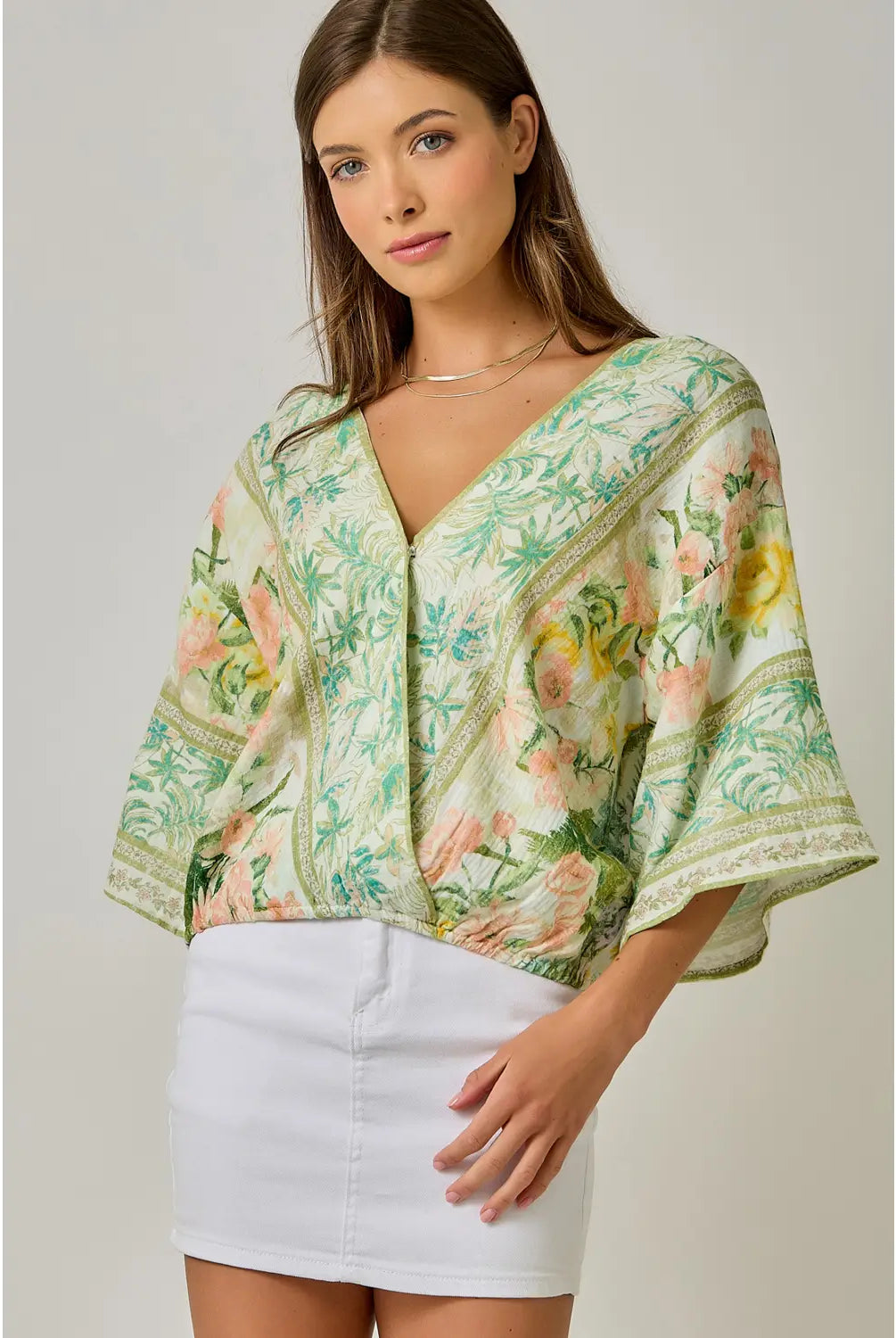 Woman wearing a floral kimono-style top with a plain background