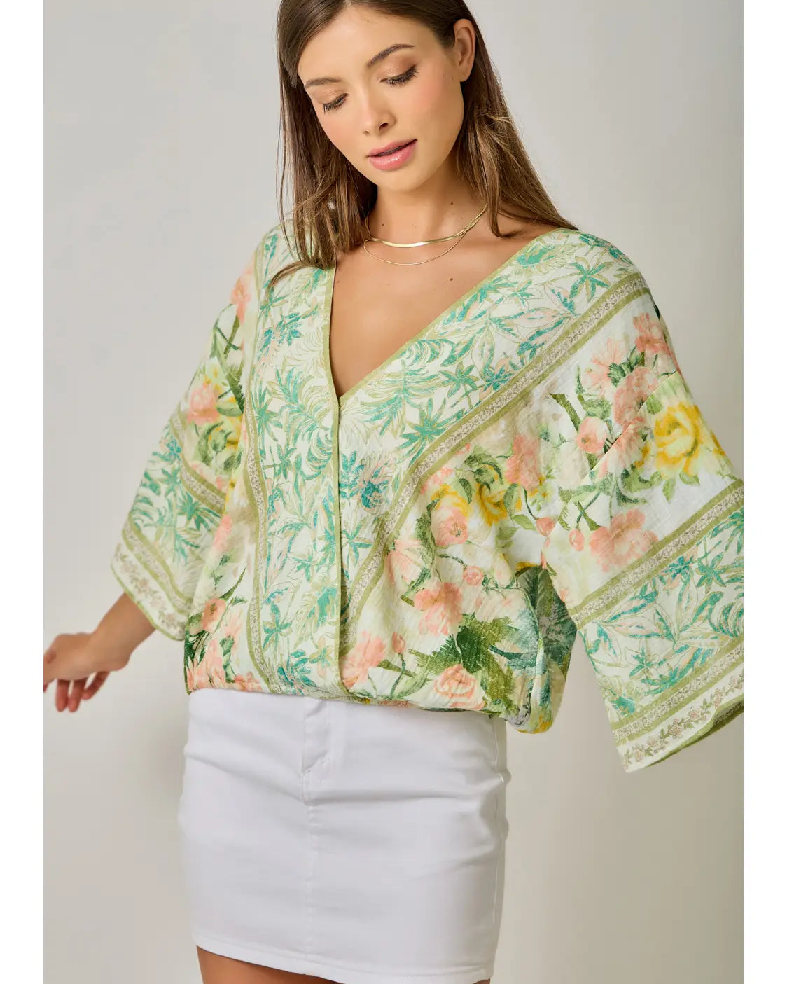 Woman wearing a floral kimono-style top with a plain background