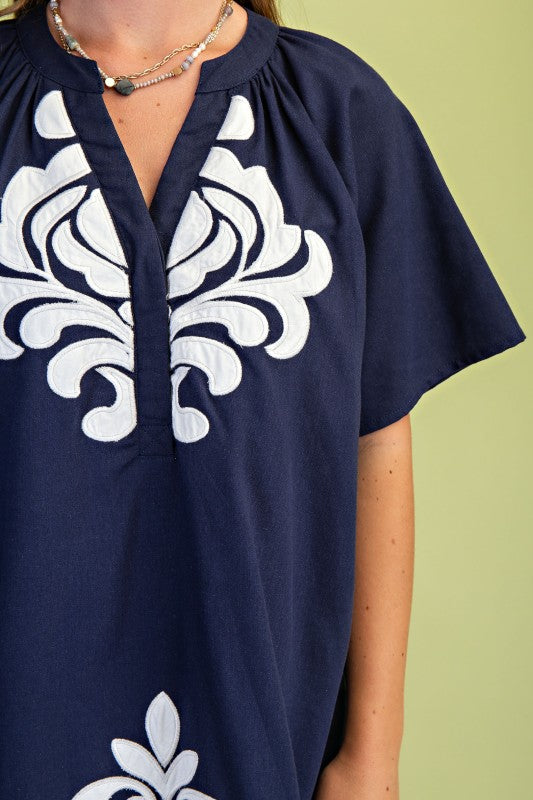Close up of Navy blue dress with white floral patterns on a green background