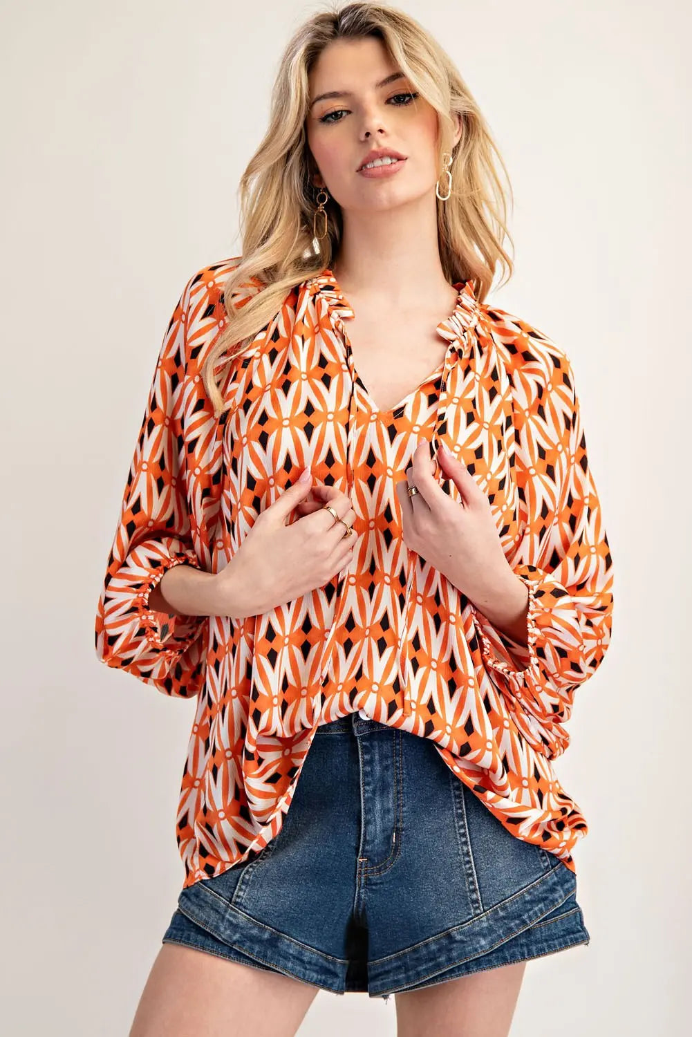 Model wearing orange ikat long sleeve blouse with jeans shorts