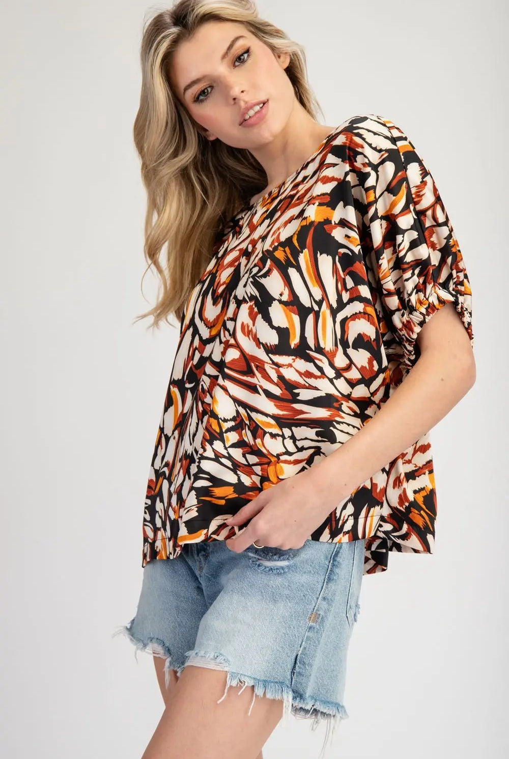 Side view of model wearing printed blouse and jeans cut off shorts