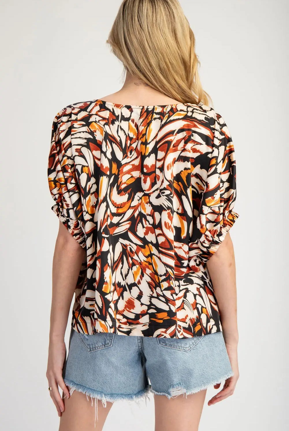 Back view of model wearing printed blouse and Jean cut off shorts