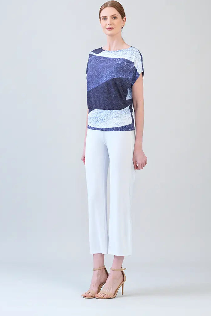 Side view of model, wearing purple and white top with white pants