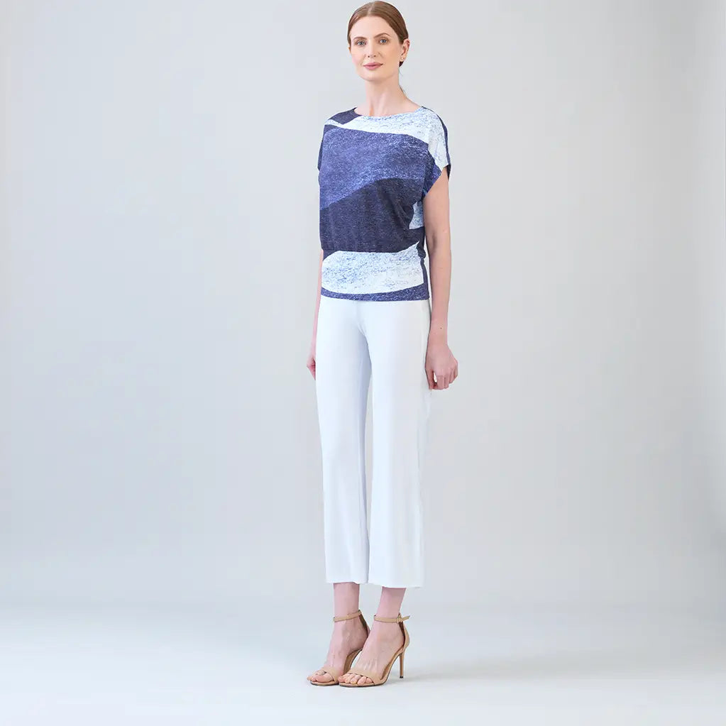 Side view of model, wearing purple and white top with white pants