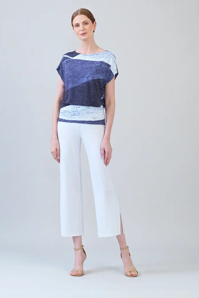 Model wearing purple and white top with white pants