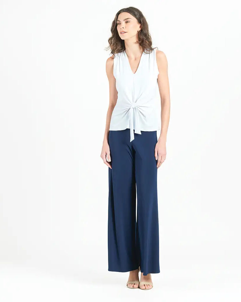 Model wearing white blouse with jeans against a white background