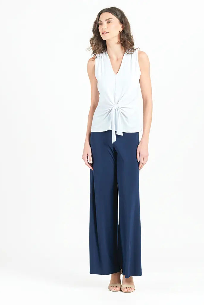 Model wearing white blouse with jeans against a white background