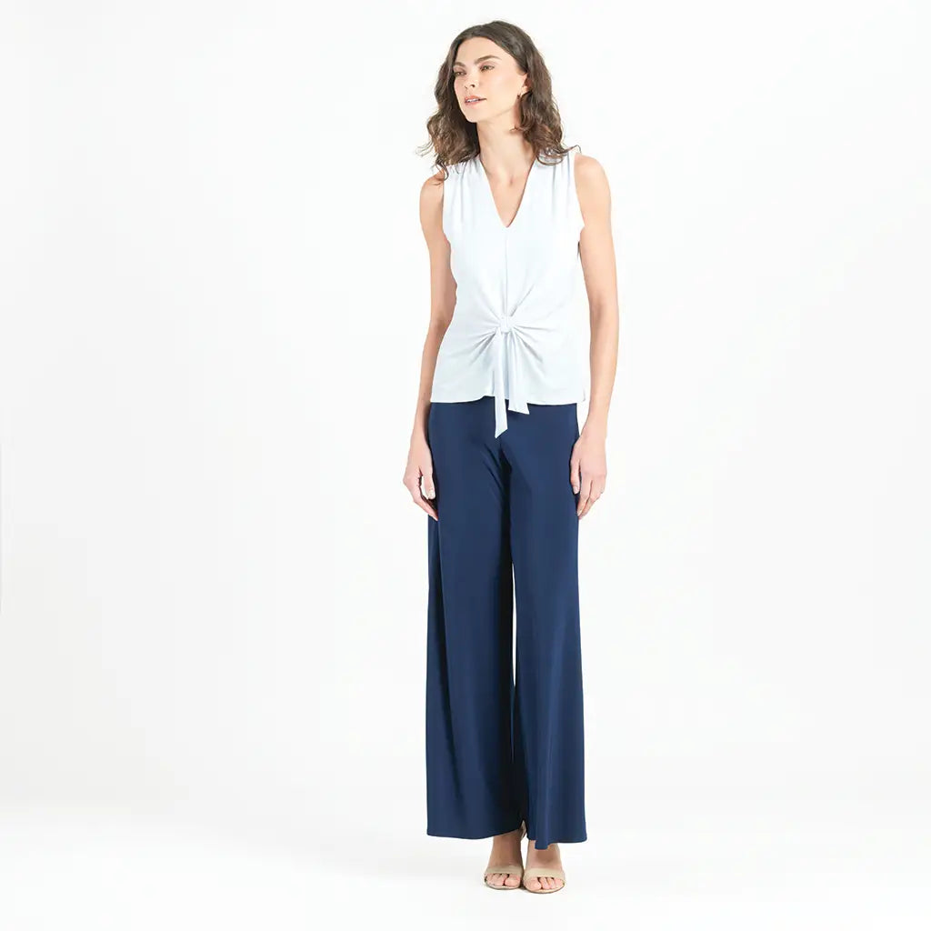 Model wearing white blouse with jeans against a white background