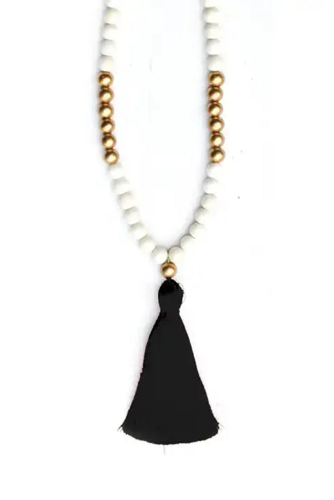White and gold bead necklace with black tassel on a white background