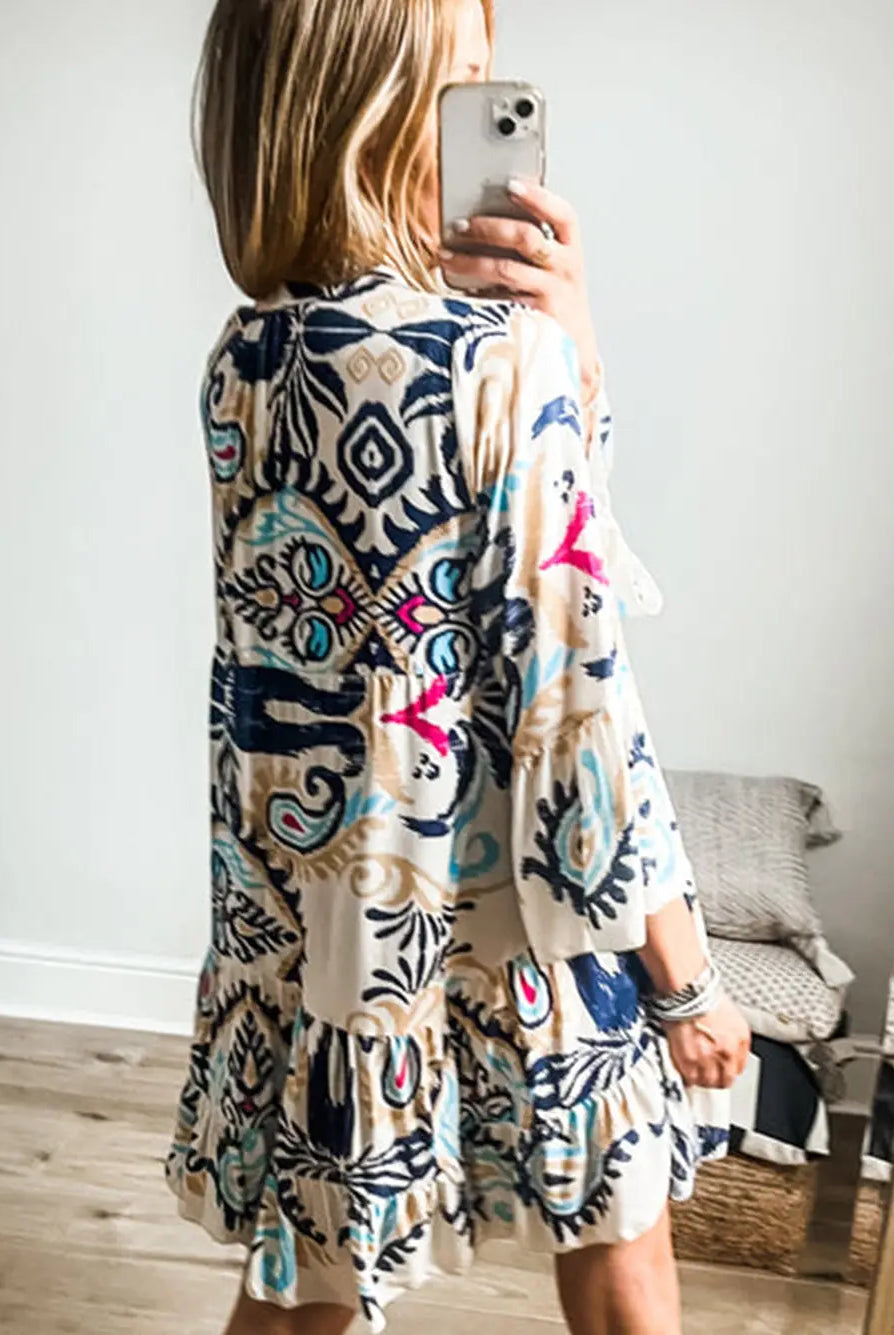 Woman wearing a colorful patterned dress taking a mirror selfie.