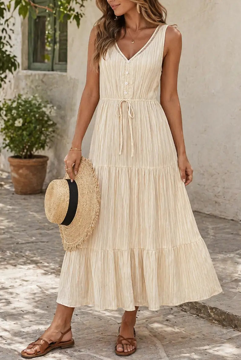 Woman in a beige dress holding a straw bag on a stone path.