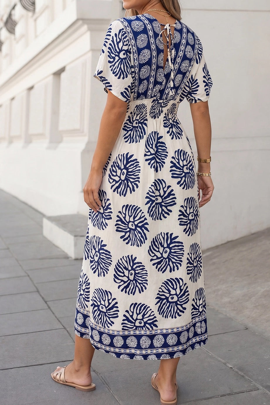 Woman wearing a blue and white patterned dress on a city street.