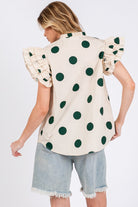 Woman wearing a polka dot blouse with ruffled sleeves 