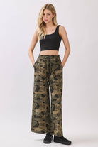 Woman wearing camouflage pants and a black top on a white background
