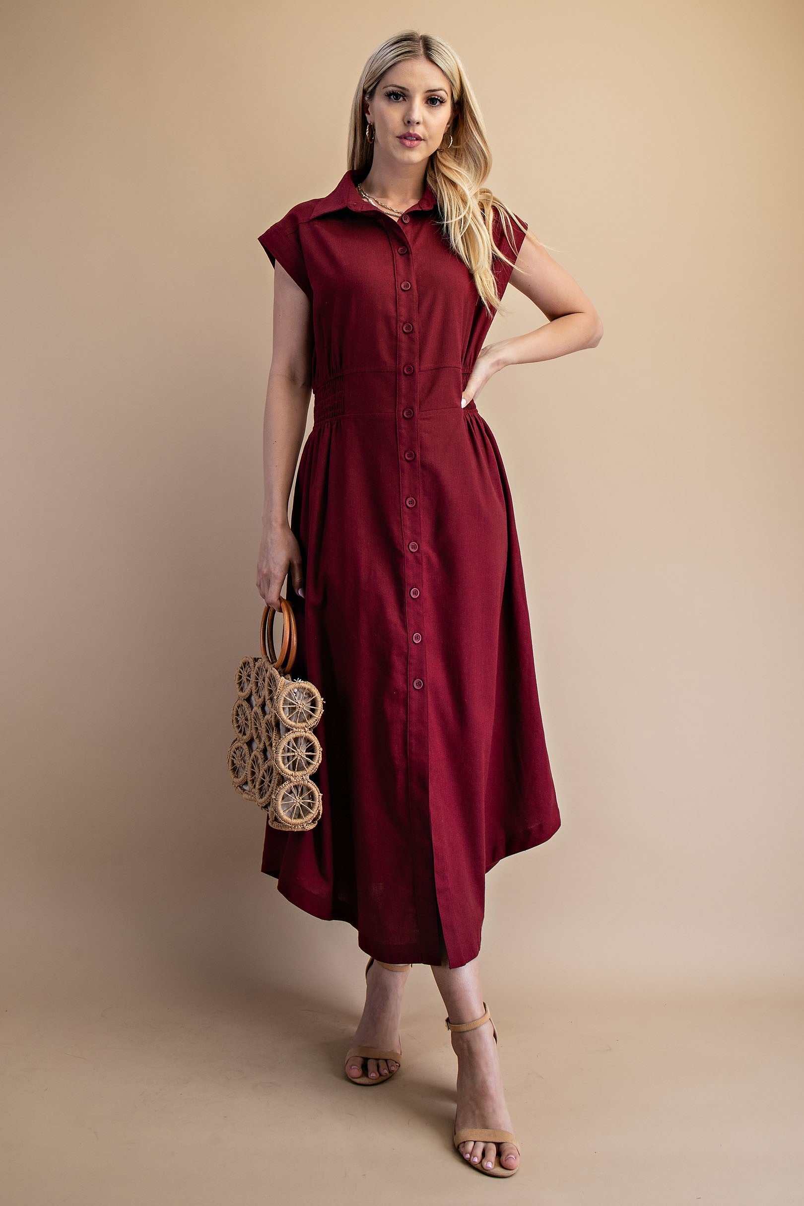 Model wearing burgundy linen dress with tan shoes and a purse in her hand
