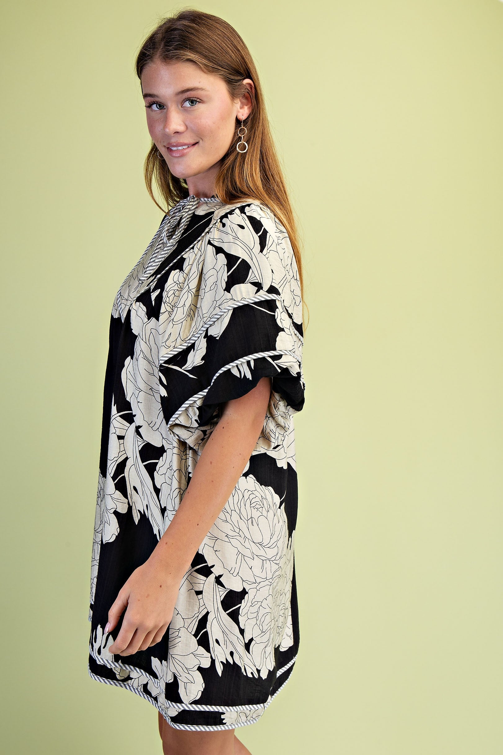 Side of woman wearing a black and white floral dress with short puff sleeves