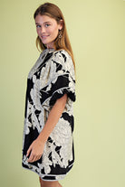 Side of woman wearing a black and white floral dress with short puff sleeves