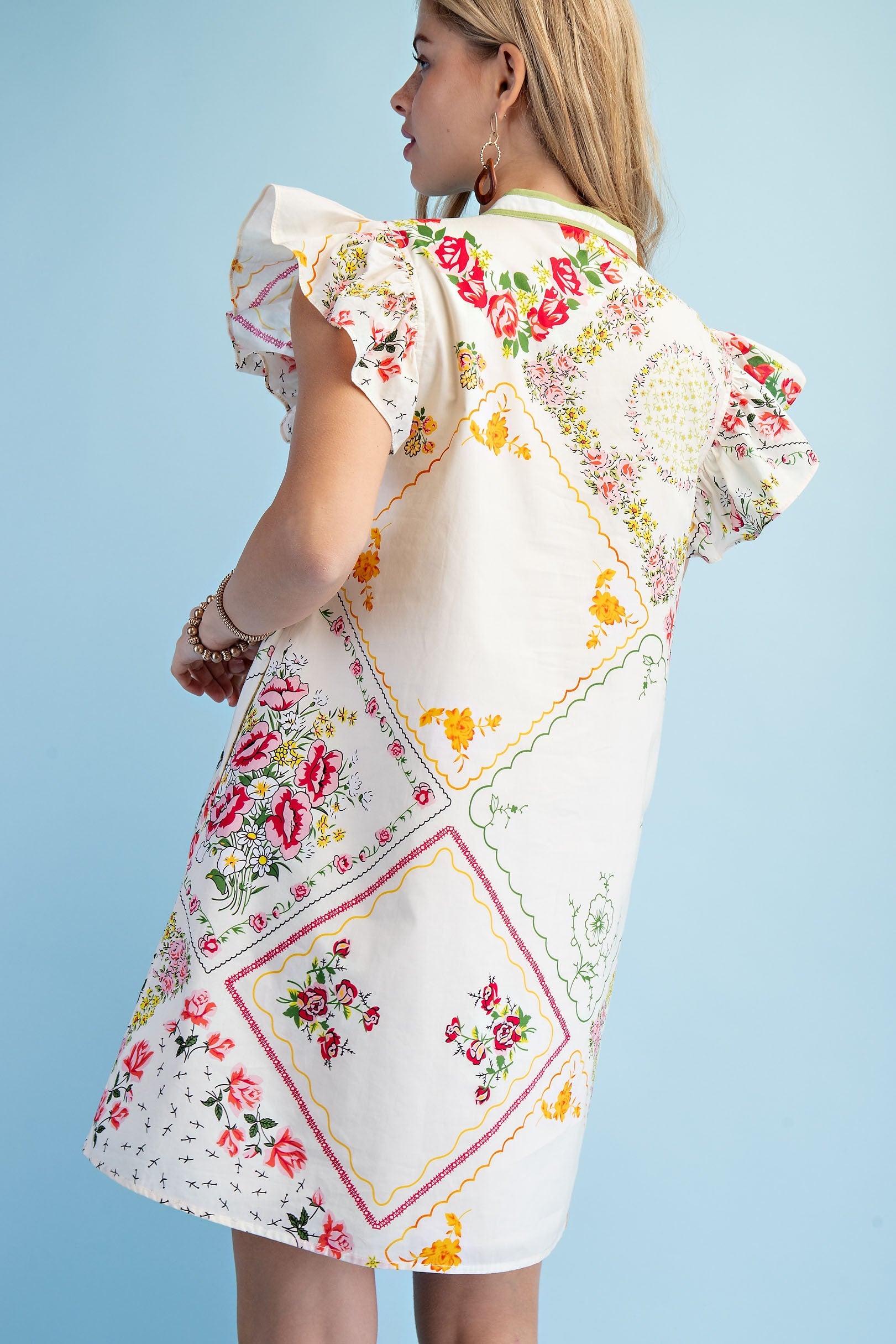 Woman wearing a dress made from a patchwork of vintage handkerchiefs against a light blue background