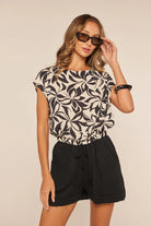 MODEL WEARING BLACK AND WHITE TOP WITH BLACK SHORTS