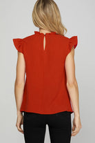 Back of woman wearing a red sleeveless top with ruffled shoulders 