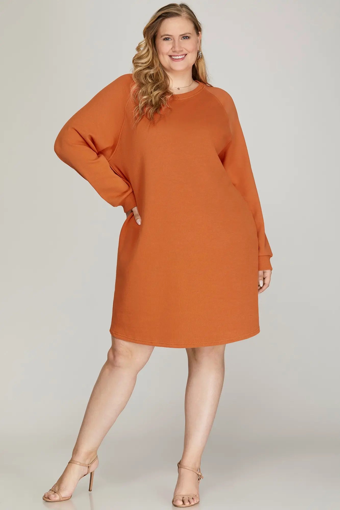 Model wearing an orange dress and nude heels