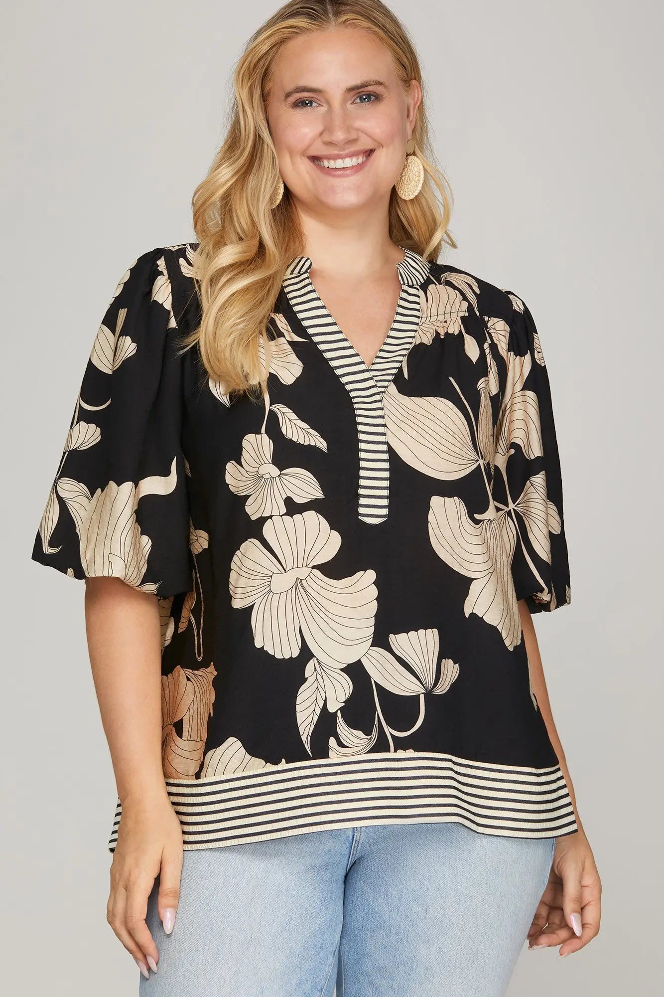 Woman wearing a black printed top with a striped trim 