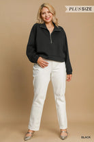 A woman modeling a black long-sleeve quarter-zip sweatshirt with white pants, standing against a solid beige studio background. Text overlays read 'PLUS SIZE' at the top right and 'BLACK' at the bottom right.