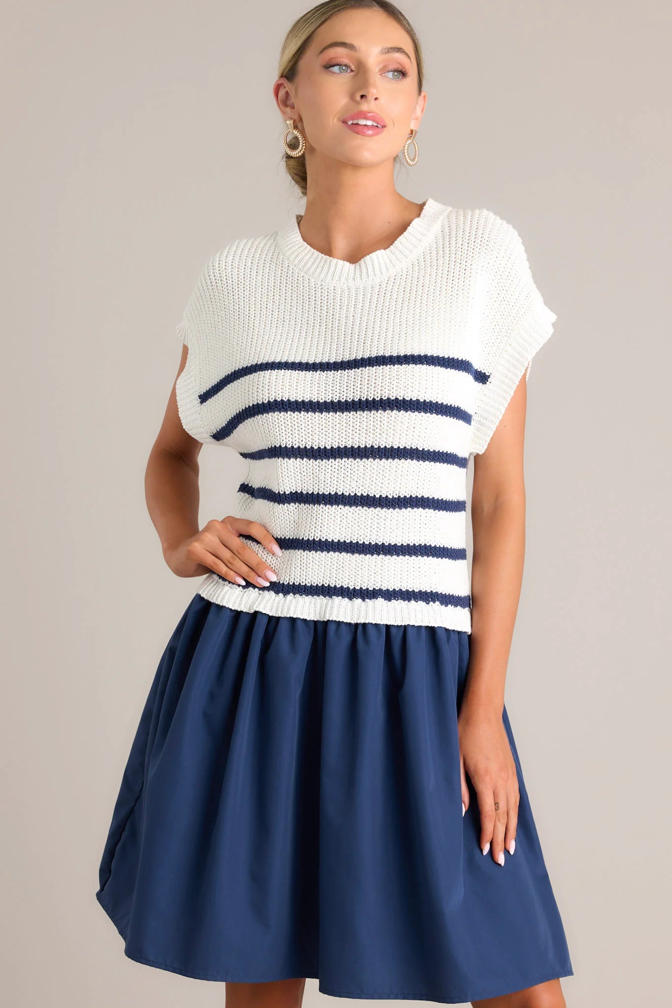 Woman wearing a white and navy striped top with a blue skirt