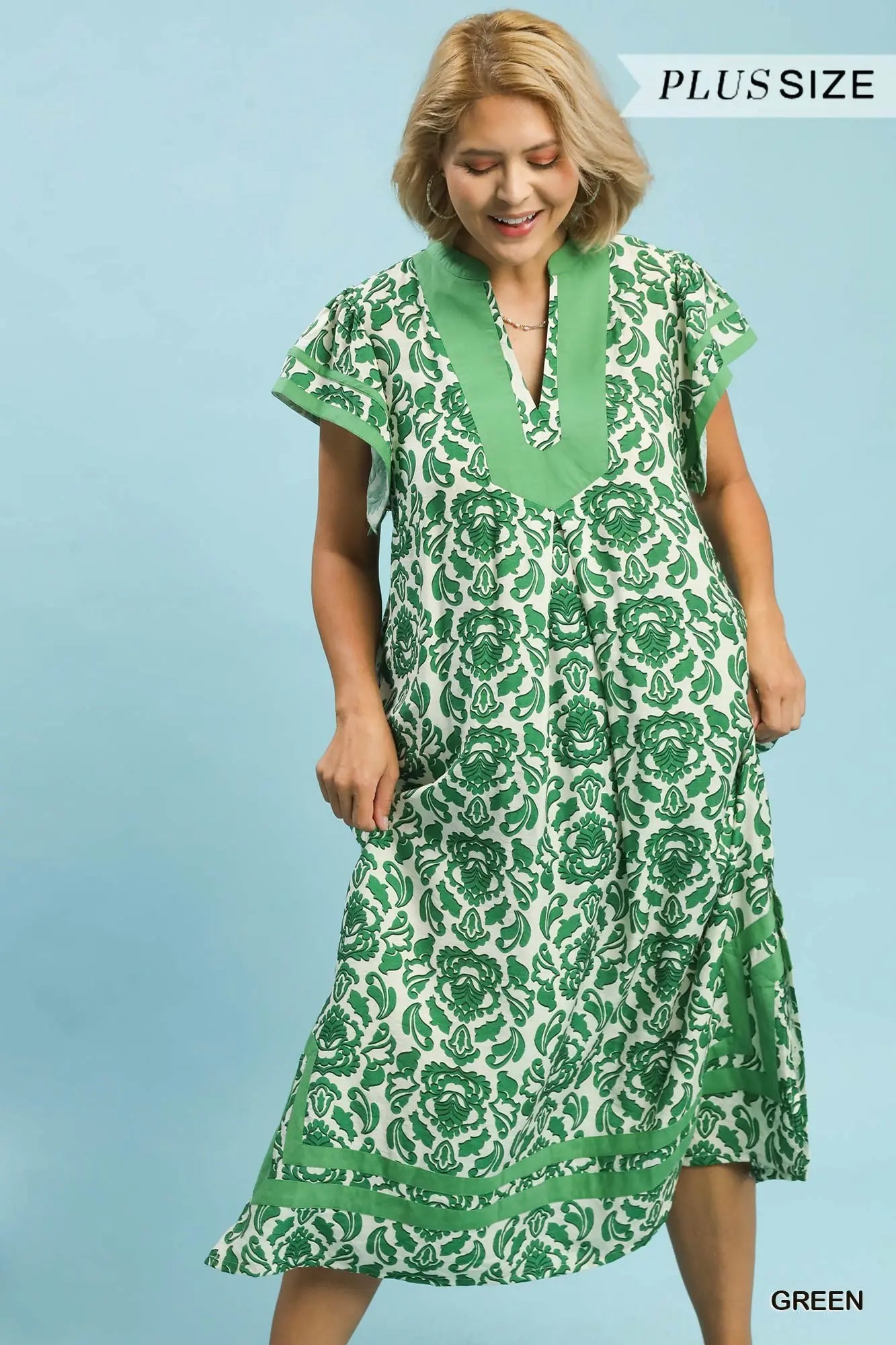 Woman wearing a green floral dress against a light blue background