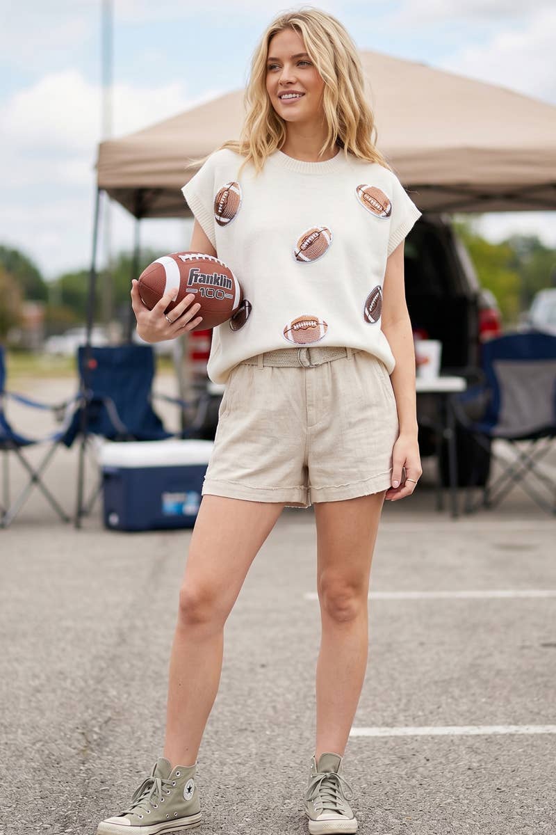 Woman holding a football with a casual outfit in an outdoor setting