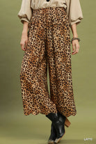 Model wearing leopard black boots against a green background