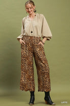 A woman modeling a beige button-up blouse and high-waisted leopard-print cropped pants against an olive green studio background. The word 'LATTE' appears in the bottom right corner.