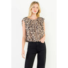 A woman modeling a leopard-print short-sleeve top with ruffled shoulders and black pants, standing against a plain white studio background.