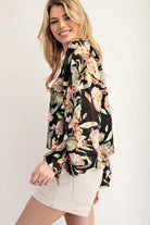 Side view of model wearing black floral top and cream shorts