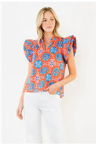 Model wearing orange printed blouse on white background 