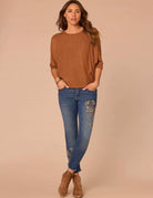 Woman wearing rust colored shirt and jeans 