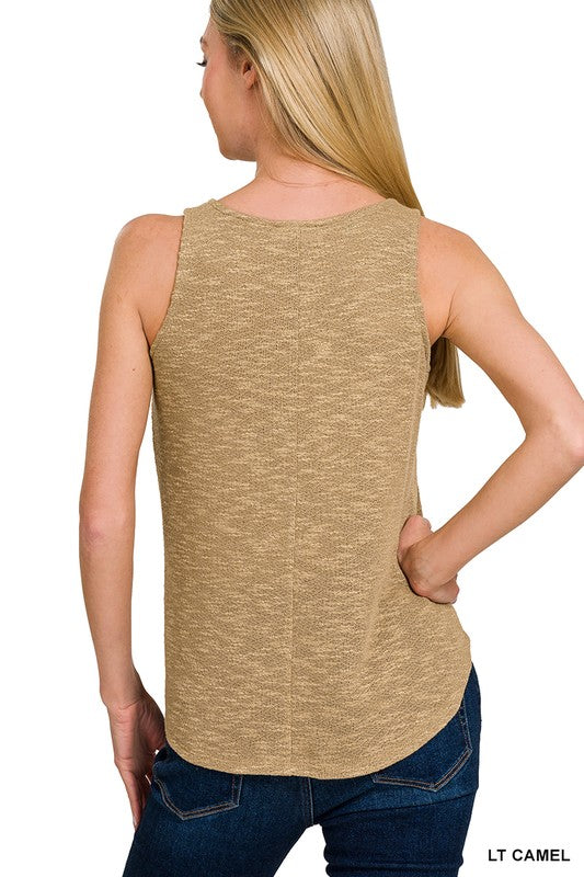 Woman wearing a light camel sleeveless top  back view with blue jeans 