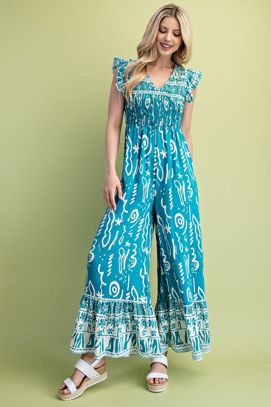 Woman wearing a teal patterned jumpsuit on a green background