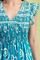 Close-up of a blue and white patterned dress with ruffled sleeves on a plain background